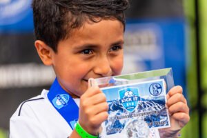 Young Kick It 3v3 Soccer participant wearing a medal and holding a first-place award plaque at the 2024 National Championship event