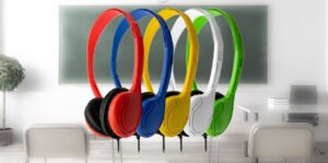 Colorful over-ear classroom headphones in red, blue, yellow, white, and green displayed in front of a classroom chalkboard, representing durable educational audio solutions from Encore Data Products