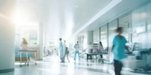 Bright hospital corridor with healthcare workers and medical staff, representing healthcare environments using hospital headphones and audio hygiene solutions from Encore Data Products
