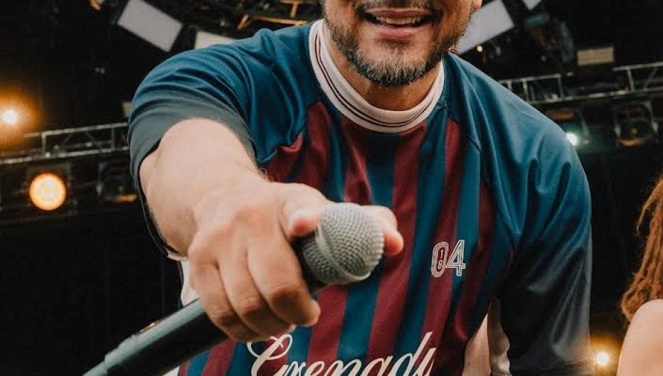 Performer wearing a custom sublimated soccer-style jersey with vibrant maroon and blue stripes while holding a microphone on stage, showcasing high-quality apparel decoration produced with Insta Graphic Systems heat transfer and sublimation technology