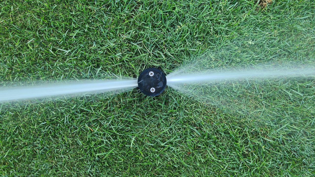 Close-up of a sprinkler head watering a healthy lawn, showcasing Aqua-Bright Irrigation LLC